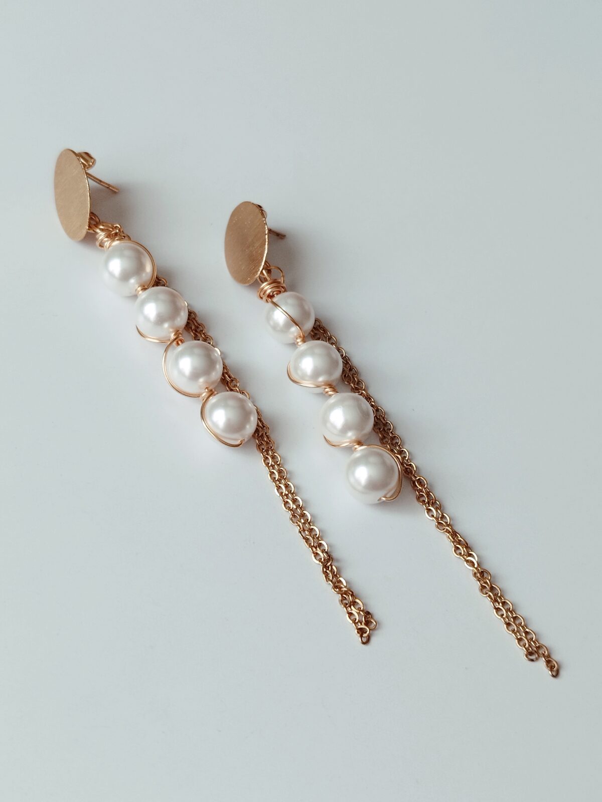 Aretes de perlas antorchados con alambre dorado, topo de bronce y cadenas de acero.